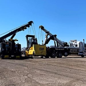 two trucks lifting construction equipment