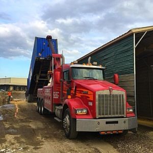 truck dumping off a dumpster at a worksite